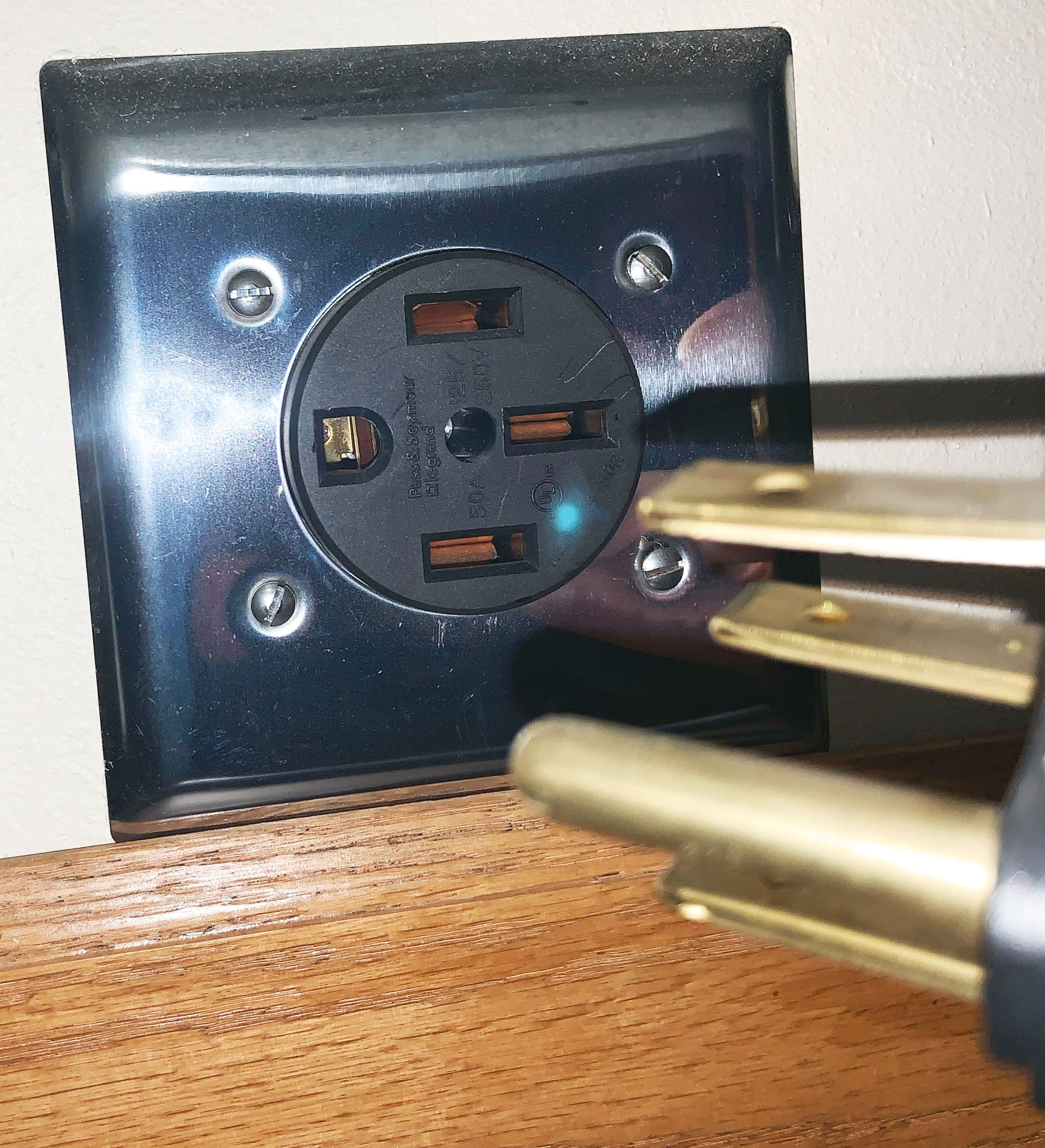 Close-up of a NEMA 14‑50 wall receptacle with a matching plug